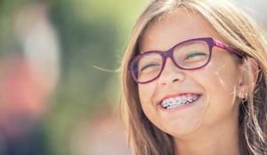 dental braces tx, girl with glasses grinning with braces