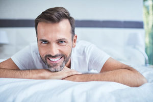 teeth whitening services pearland texas, man on bed smiling