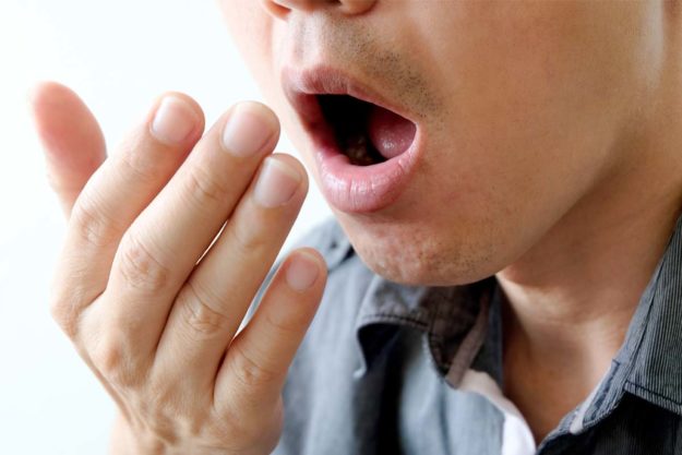causes-of-bad-breath (3) man checking to see the causes of bad breath