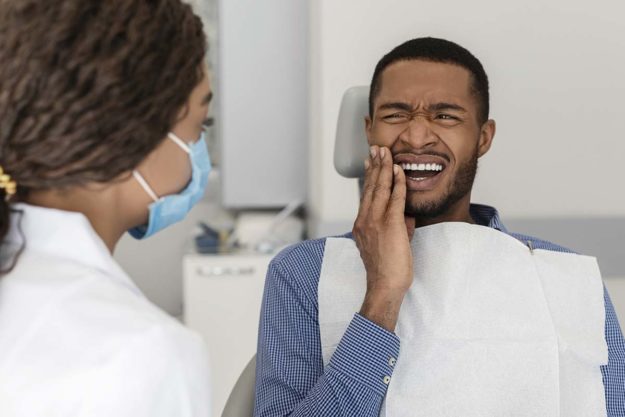symptoms-of-a-cavity individual holding jaw showing symptoms of a cavity