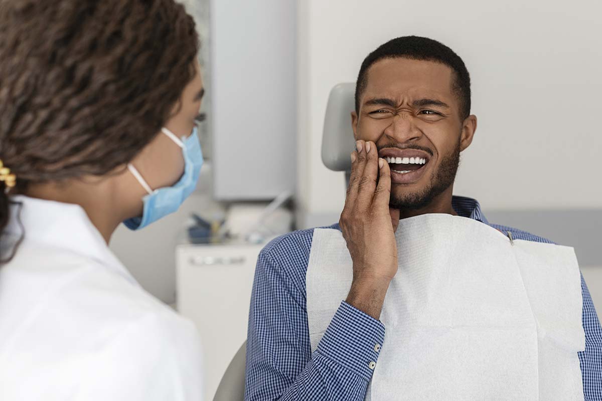 symptoms-of-a-cavity individual holding jaw showing symptoms of a cavity